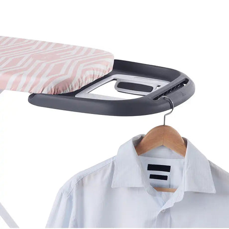 Ironing board with a shirt on a hanger against a white background