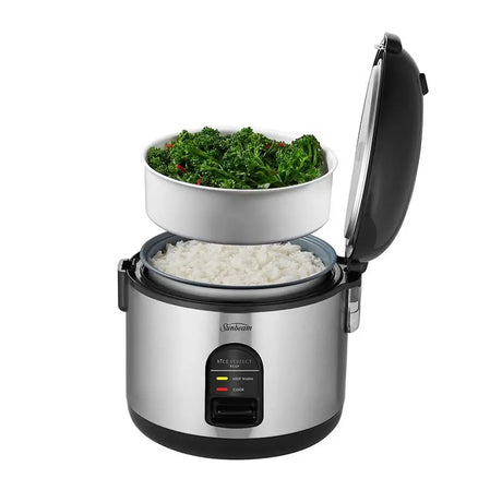Rice cooker with a bowl of greens on top and rice inside, on a white background