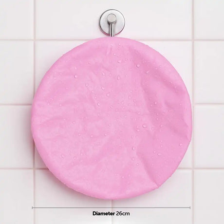 A pink round shower curtain cover with water droplets, hanging from a silver wall hook on a white tiled wall, with a dimension label indicating a diameter of 26cm.