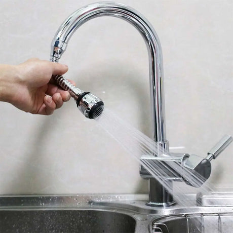 Person holding a faucet nozzle attached to a kitchen sink with water flowing.