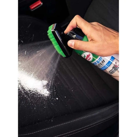 Person cleaning car interior with a brush and spray bottle