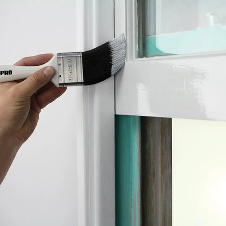 Person painting a window frame with a paintbrush