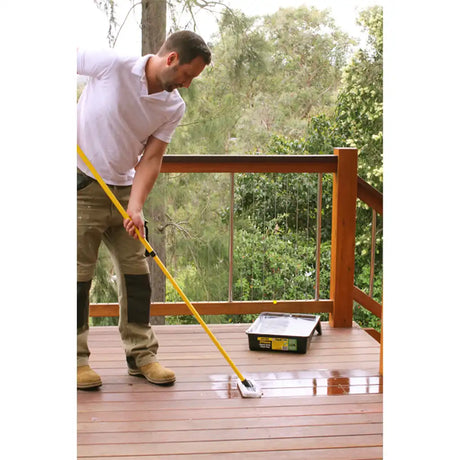 Man cleaning a wooden deck with a brush and bucket