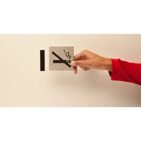 Hand pressing a no smoking sign on a wall