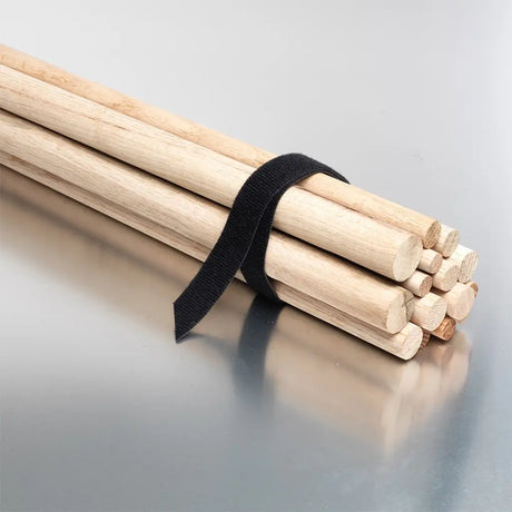 Wooden drumsticks bundled together with a black strap on a reflective surface.