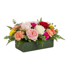 Colorful flower arrangement in a rectangular wet form planter on a white background